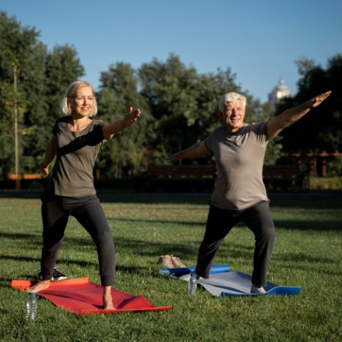 Mature couple doing yoga outside